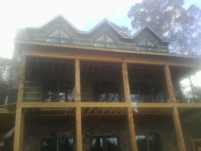 Dormers and porch framing on a large log home under construction — Roof Coating work by our crew in Brooten