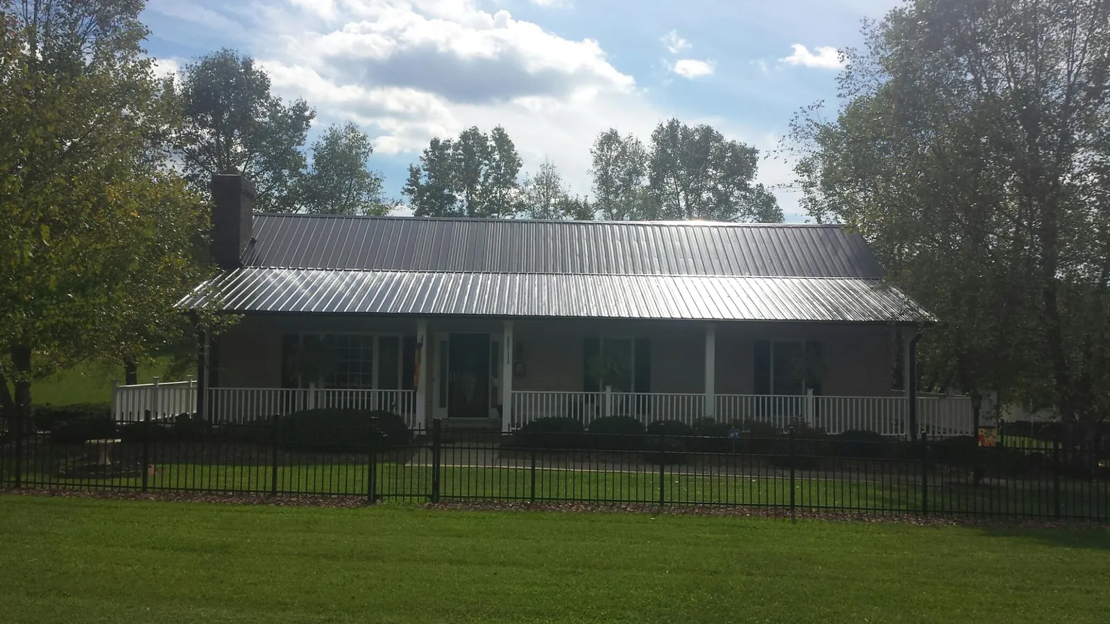 Gray metal roof on a brick ranch with a full width front porch — Gutter Guard Installation work by our crew in Brooten