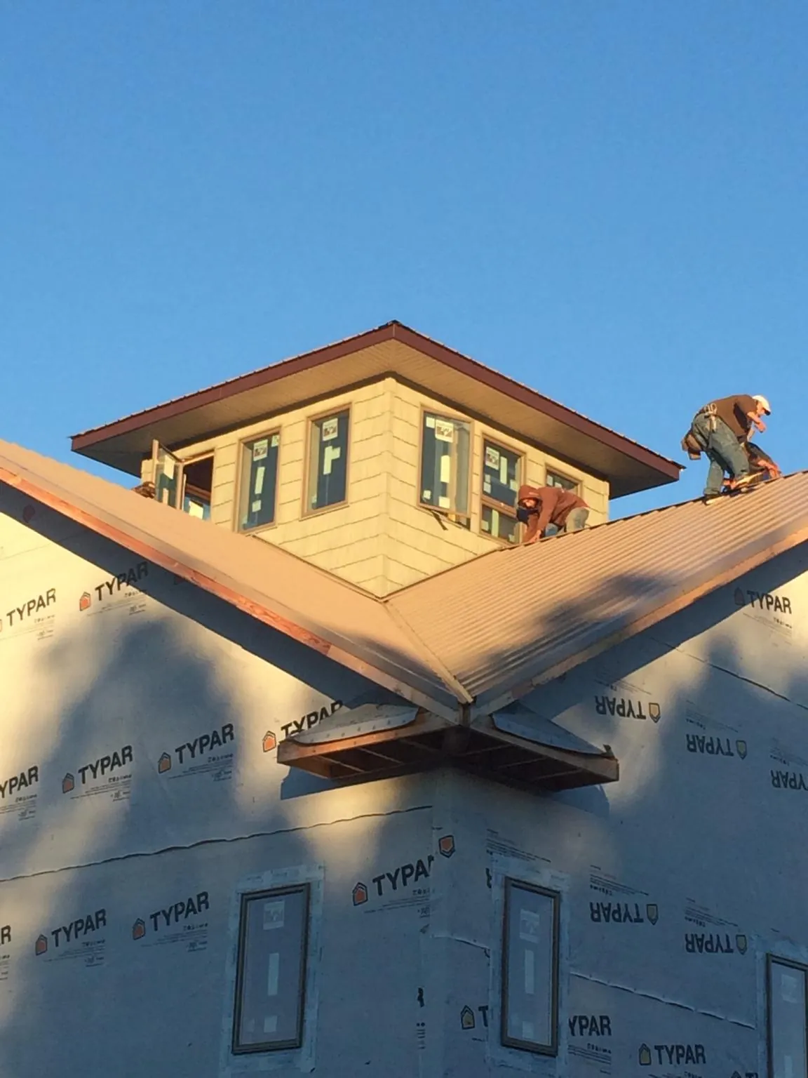 Roofers working around a rooftop cupola on a new metal roof at sunset — Roof Waterproofing in Brooten by Roofing Brothers